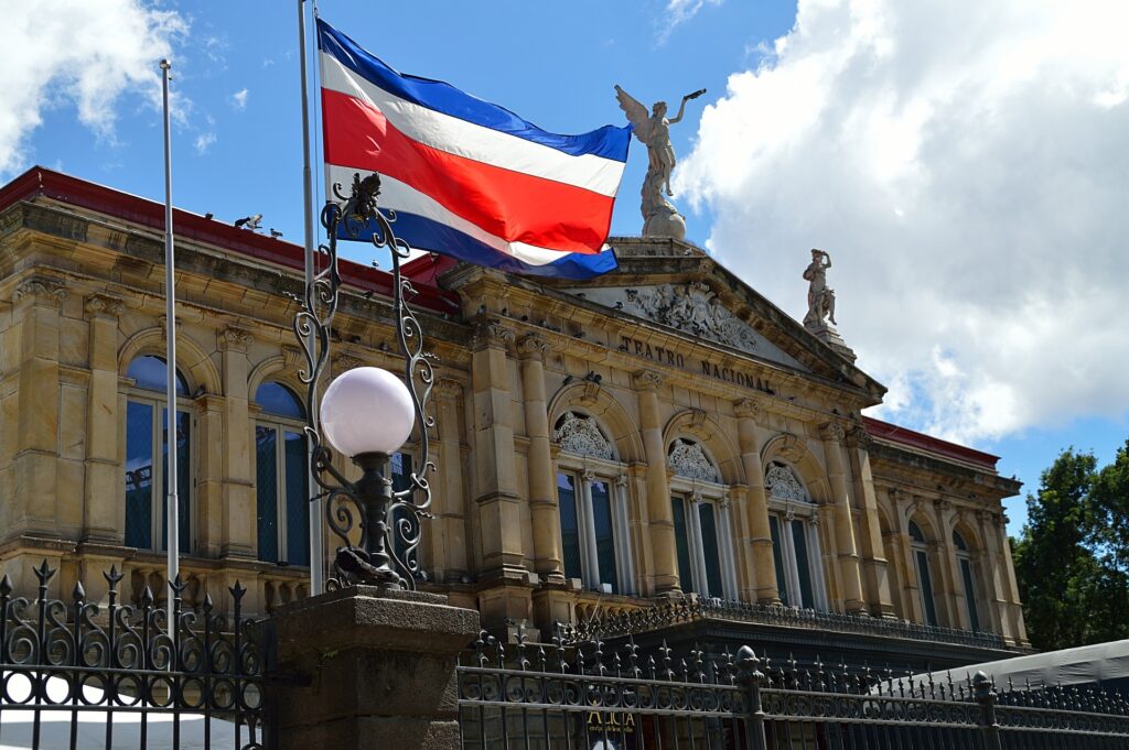 an image with the Costa Rica's flag raised in a pole in front of the Teatro Nacional building